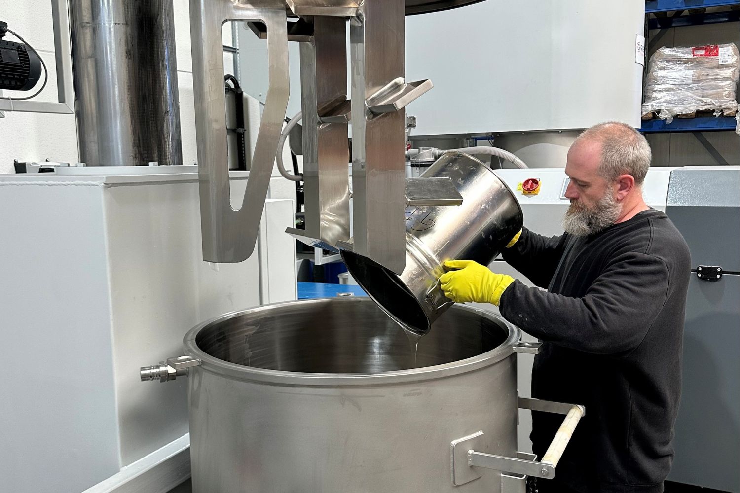 A man pours the contents of a bucket into a large machine